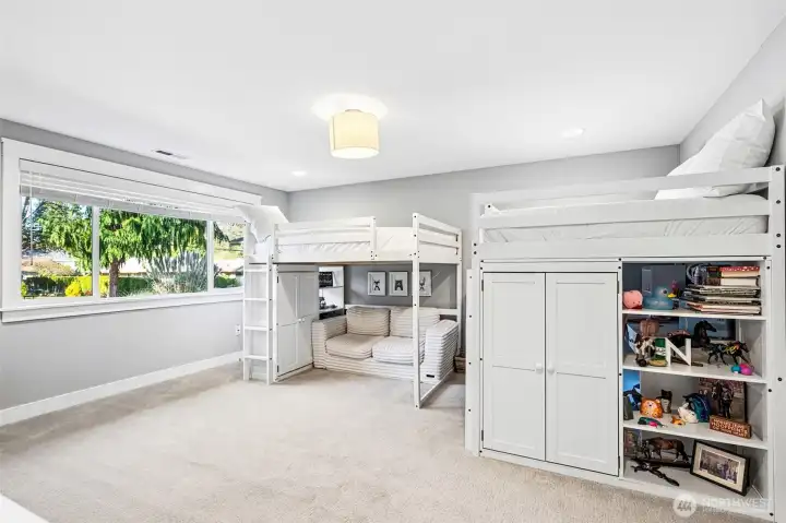 This second primary suite brings serious flexibility to the floor plan. At roughly 15 by 18 feet, it’s a large, comfortable space with a big picture window overlooking the front yard that keeps the room filled with natural light. The soft dove gray walls and warm latte-toned carpeting create a calm, cohesive feel that matches the rest of the home, while the drum-style light fixture adds a clean, modern touch overhead. Having its own attached bathroom and walk-in closet makes this feel like a true suite, not just another bedroom. It’s a great option for guests, extended living arrangements, or anyone who appreciates a little extra space and privacy.