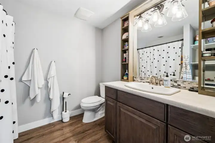This ensuite bathroom adds another layer of convenience to the second primary suite. A full jetted tub and shower combination keeps it versatile, while the built-in shelving around the mirror offers practical storage that helps keep things organized and uncluttered. It’s a clean, straightforward space that does exactly what you want it to do. The walk-in closet nearby rounds it out nicely, giving this suite a true sense of independence and making it a great option for guests or extended living arrangements.