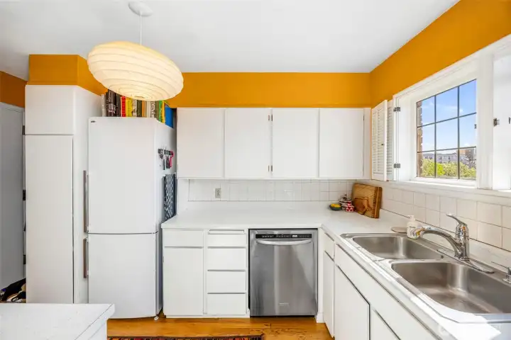 Cheerful kitchen with vibrant color, generous prep space, and oversized windows bringing in natural light throughout the day.