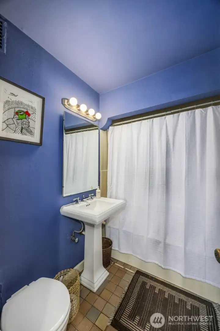 Vintage-inspired bathroom with colorful personality, pedestal sink, and classic tile flooring true to the home’s character.