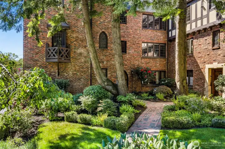Lush landscaped courtyard offers a peaceful garden setting tucked within the iconic brick Tudor architecture.