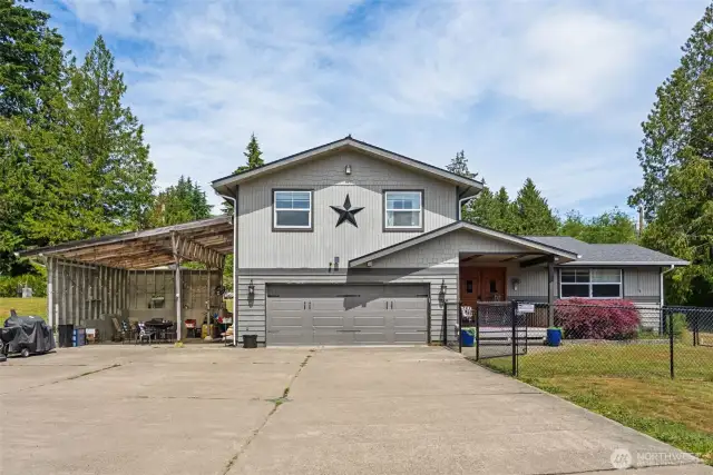 Front exterior shot captures the expansive driveway & versatile covered parking area.