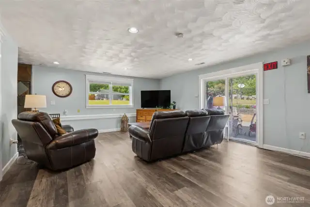 Spacious lower-level view showcasing generous room size & easy access to the outdoors through the sliding glass door—ideal for everyday living or entertaining.