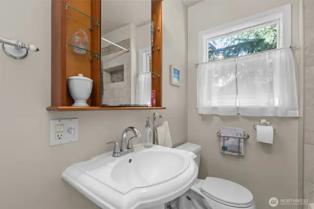 Full bathroom (main floor) has tiled shower with built-in shelf, ceramic tile flooring, and small closet.