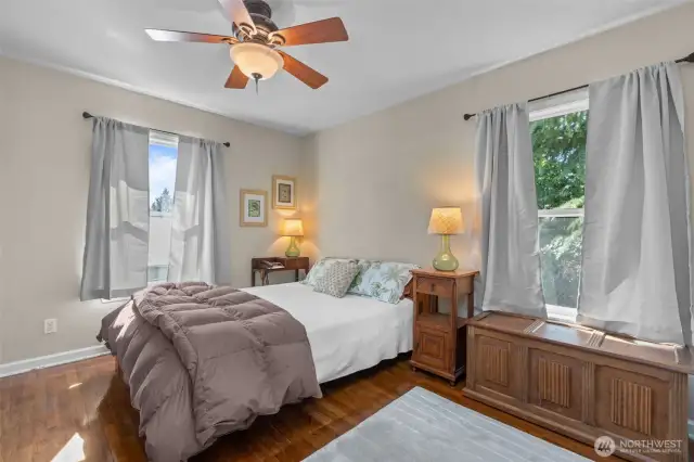 Primary bedroom with oak flooring, plenty of natural light, and partial mountain view.