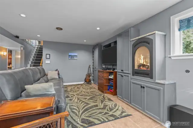 Rec room on lower floor with gas fireplace, built in media storage, and ceramic tile flooring.