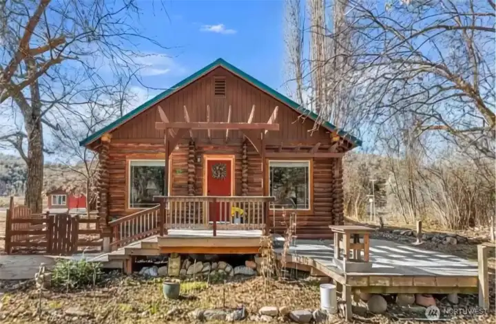 Front of Home -  Classic log home charm welcomes you with a covered front porch and spacious wraparound deck—perfect for morning coffee, evening sunsets, and soaking in the peaceful Purtteman Gulch setting.