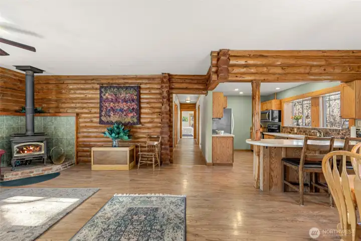 Welcoming entry opens to an inviting great room with rich log walls, warm wood flooring, and open flow to the kitchen — comfortable level living with true Northwest character.