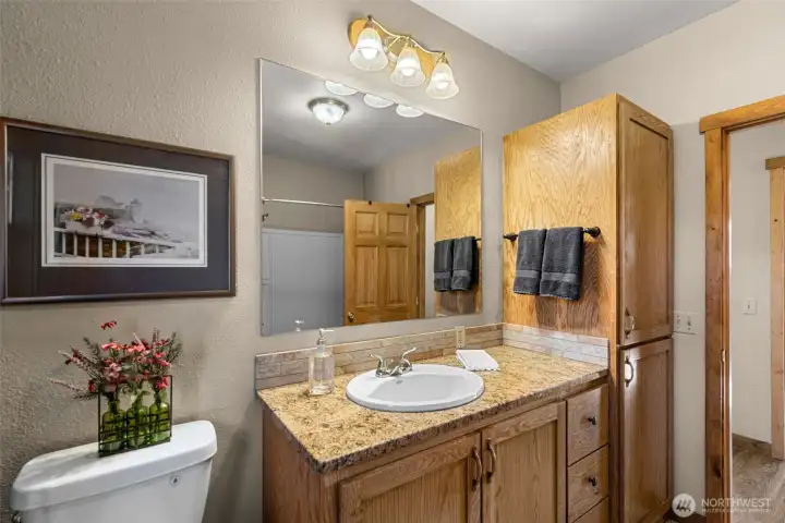 Main Bathroom Vanity & Storage =  Spacious vanity with granite countertop, ample cabinetry, and full tub/shower—designed for functionality while maintaining the home’s inviting cabin style