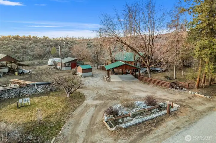 Bird’s-eye view of the full property layout -showcasing home, shop, well house, pole barn, and covered parking — all thoughtfully arranged for function and privacy.