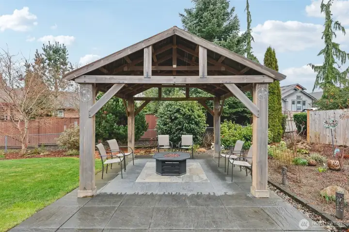 Beautiful backyard gazebo with slate flooring and fire pit, perfect for outdoor gatherings.