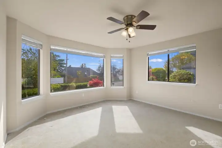 Living space with a corner of large windows bringing in natural light and views of the surrounding yard