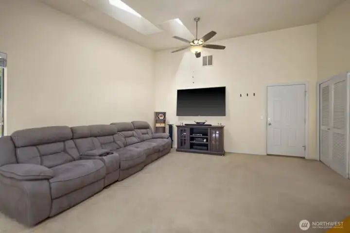 Additional living area with vaulted ceilings, ceiling fan, and overhead skylights adding natural brightness