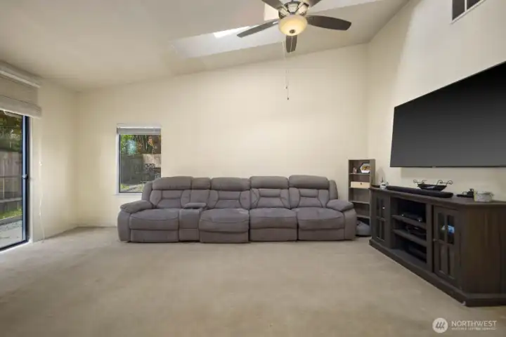Open living space with high ceilings, wall-mounted TV area, and flexible layout for seating or media use