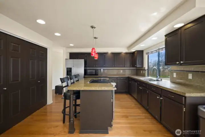 Kitchen centered around an island with built-in cooktop and additional prep space