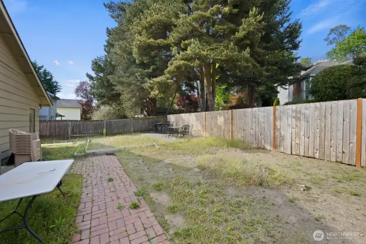 Fully fenced backyard with patio space and room for outdoor seating or gardening.