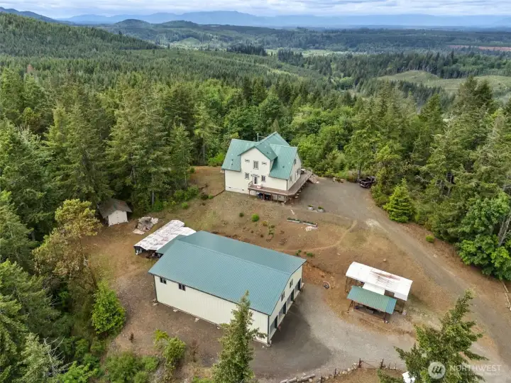 From above, you really start appreciating just how extensively this property was planned because everything has its place while still keeping the home itself positioned front and center for the absolute best views and overall living experience. The oversized 3,000-square-foot shop dominates the center of the property and is actually larger than the house, creating a dream setup for hobbyists, collectors or anyone whose lifestyle requires serious storage and workspace capacity. Off to the right sits the covered RV parking area complete with hookups and gazebo-style deck space, while behind the shop are TWO additional adjustable-height carports ideal for trailers, campers, boats, RVs or extra vehicle coverage depending on future needs. There is even an additional garden shed tucked to the side for even more practical storage. What works so well here though is that all of these utility & recreational structures are intentionally placed behind the home, preserving those jaw-dropping views.