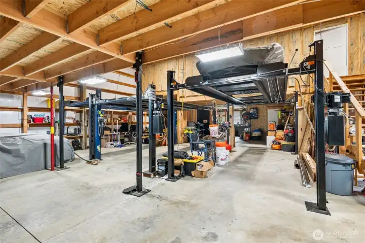 This shop is absolutely outrageous in the best possible way. At 3,000 square feet and FOUR full bays, it is actually larger than the house itself, which honestly tells you a lot about the personality of this property before you even step inside. Built with metal siding and a metal roof for durability and low maintenance, the space is set up to accommodate up to 12 vehicles and includes THREE automotive lifts that remain with the property, creating an absolute dream setup for collectors, mechanics, hobbyists or anyone whose current garage situation consists mostly of creative frustration and strategic parking negotiations. The scale here is seriously impressive, and the upstairs unfinished apartment and additional bonus room space accessed by the staircase adds even more flexibility for future expansion, guest accommodations, workspaces or recreational use. This is not “extra garage space.” This is full-blown lifestyle infrastructure.