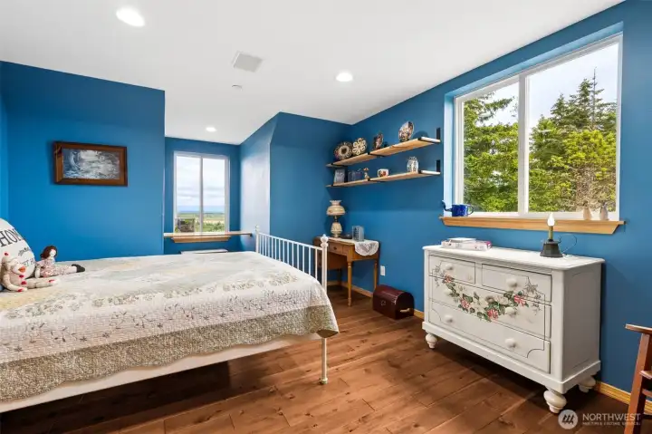 This upstairs bedroom mirrors the same generous sizing and peaceful elevated atmosphere found throughout the rest of the upper level while adding another thoughtful feature that makes the space incredibly versatile for modern living. Along with the gorgeous hardwood floors, soft blue wall color and beautiful treetop views pouring through the oversized window, the room also includes a built-in desk alcove perfectly positioned for remote work, studying, gaming setups or creative projects with a spectacular natural backdrop instead of staring at a blank apartment wall while slowly losing the will to answer another email. The room feels bright, calm and wonderfully tucked into the surrounding landscape, and having dedicated desk spaces built into both upstairs bedrooms adds tremendous flexibility depending on how future owners want to utilize the rooms over time. The property currently uses Starlink internet service, which has become a huge asset for more rural and acreage properties.