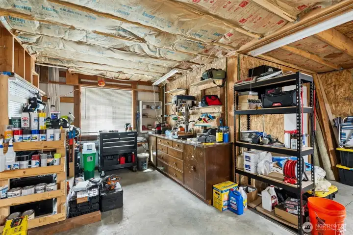 This portion of the shop really highlights how versatile and functional the entire structure is because it is not just oversized parking space, it is a fully usable working environment designed to support serious hobbies, projects and long-term flexibility. The open workspace layout leaves ample room for tools, fabrication areas, storage systems and vehicle access while still keeping the overall space feeling organized and highly usable. Toward the back of the shop you will also find a dedicated reloading room featuring FOUR bolted and welded safes that remain with the property, creating substantial secure storage already built directly into the setup. And because this property apparently refuses to stop overdelivering practical details, there is also a brand-new mini washer and dryer in the shop that has never even been used and will stay with the home, making future apartment use, cleanup or extended shop projects dramatically more convenient.