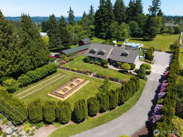 Welcome to your dream retreat—this breathtaking aerial view showcases the grand entry, lush front garden, impressive home, resort-style pool & sprawling yard. A private oasis where elegance meets everyday comfort