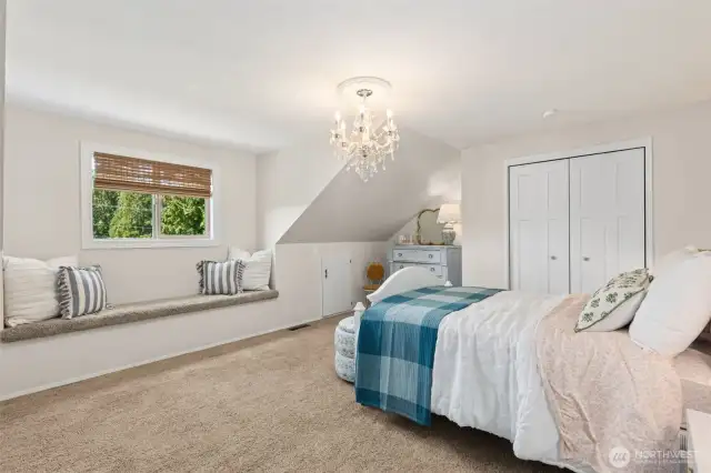 Delightful bedroom features a built-in window bench & a statement chandelier—blending charm & elegance in a space that feels both cozy & elevated