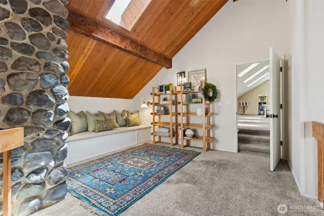 Stunning loft retreat features a built-in reading bench & cozy skylight tucked behind the river rock chimney—offering charm, light & a peaceful place to unwind above it all