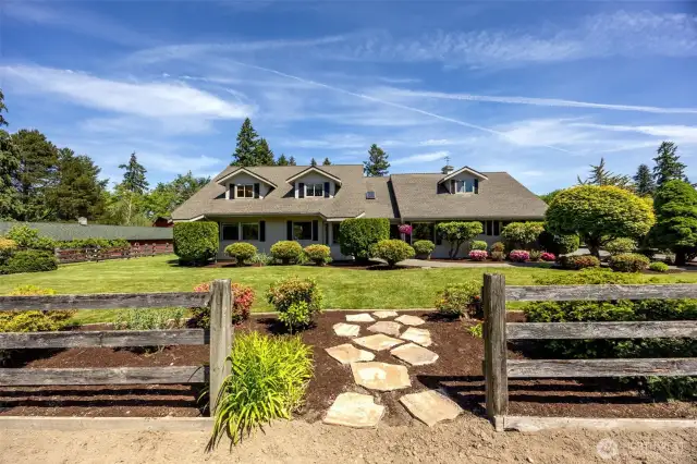 A thoughtful gap in the split rail fence features stone pavers that create a charming pathway—connecting the home to the garden with ease & enhancing the flow of the front yard design