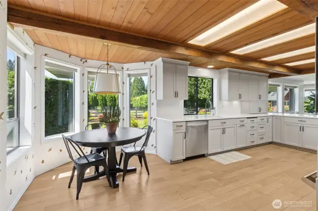Bright dining nook flows seamlessly into a spacious kitchen—endless windows fill the space w/ light, while expansive counters offer room to gather, prep & entertain
