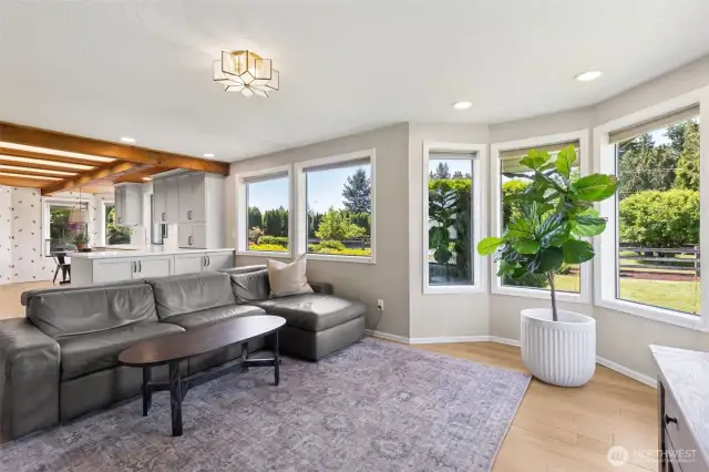 Sun-drenched living space offers a serene retreat—towering windows showcase lush garden views, creating a tranquil backdrop for everyday relaxation or elegant entertaining