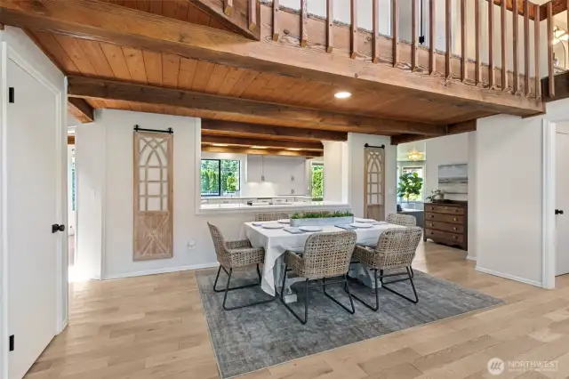 View from dining room into kitchen reveals stunning architectural flow—open catwalk above overlooks the great room, adding light, height & a dramatic sense of space