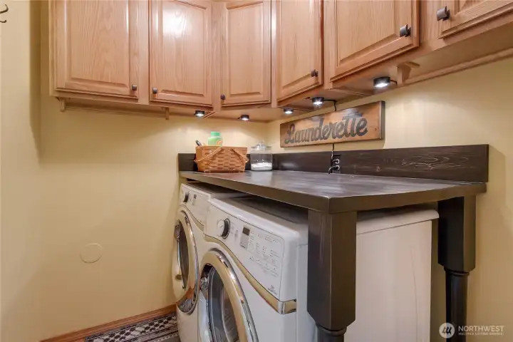 Upstairs laundry area with custom folding table, plenty of storage and lighting. W/D included.