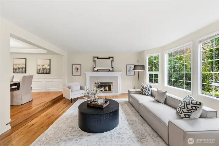 Formal living room with large windows and wood-burning fireplace.
