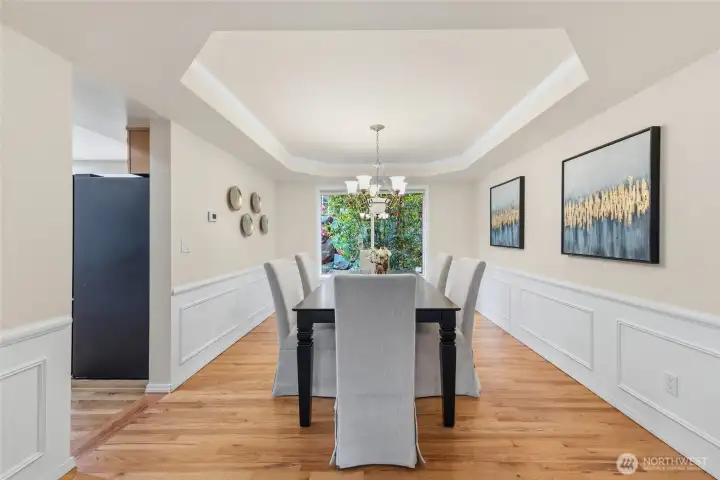 Formal dining room with tray ceiling and wainscoting.