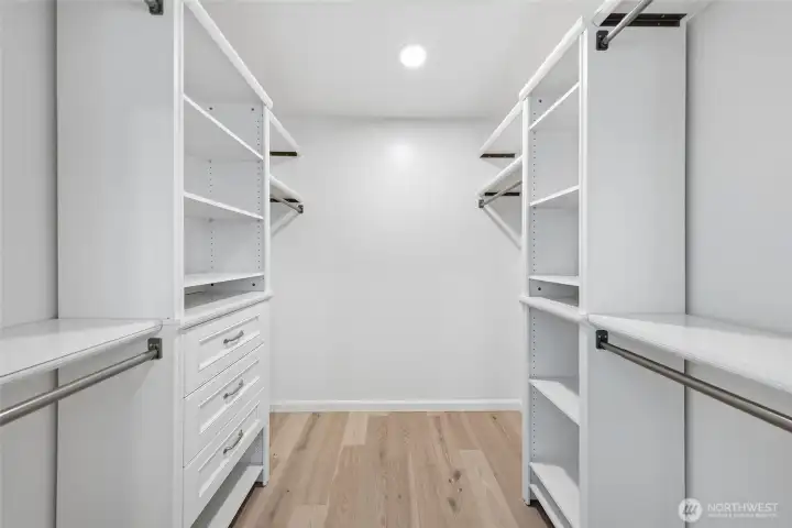 Walk-in closet with built-in shelves and drawers in primary suite.