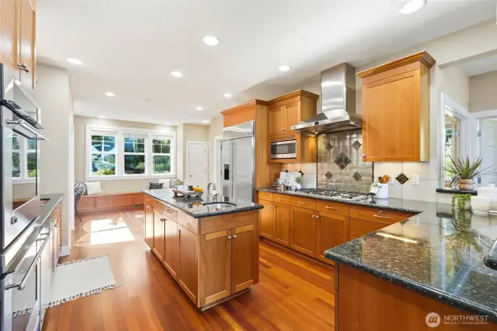 Beautiful chef's kitchen with custom cabinetry, granite counters, island with a sink, pantry and GE Monogram SS appliances.