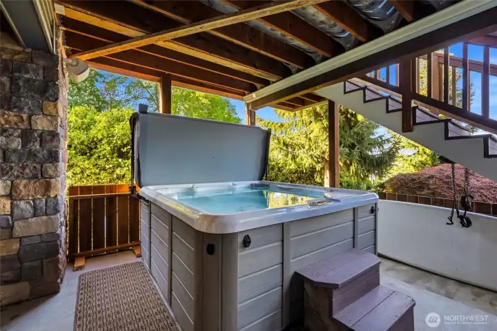 Hot tub on the covered patio area.  Deck above has a rain-catchment system so you can always stay dry.