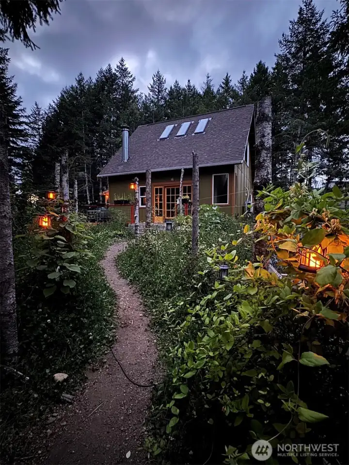 Follow the softly lit garden path beneath the trellis and experience the peaceful welcome that makes coming home feel like leaving the world behind.