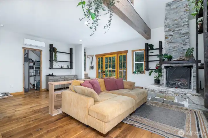 The stacked stone fireplace, exposed timber beam, and warm wood finishes create a living room that's both inviting and full of character.