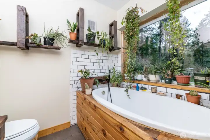 Natural materials, custom craftsmanship, and a large picture window create a bathroom designed to feel connected to the outdoors.