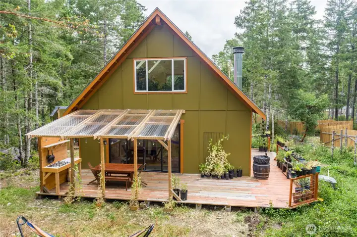 The thoughtfully designed backyard blends outdoor living, gardening, and nature into one connected space, all tucked behind the privacy of towering evergreens.