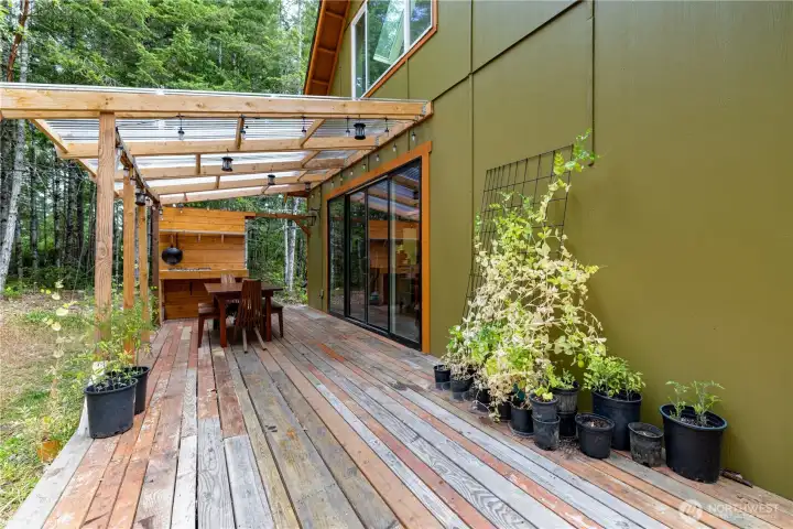 Designed for year-round outdoor living, the covered deck features an outdoor kitchen and creates the perfect space to gather, cook, and enjoy the peaceful forest setting.