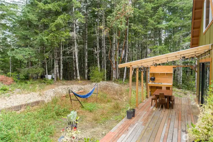 Cook, dine, and unwind beneath the covered outdoor kitchen, where meals are best enjoyed surrounded by the sights and sounds of the forest.