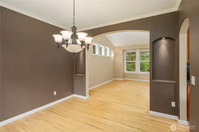Dining room to living room view.   Hardwood floors, crown molding, sconces, custom lit art nooks, transom windows and large picture windows.  So many nice features.
