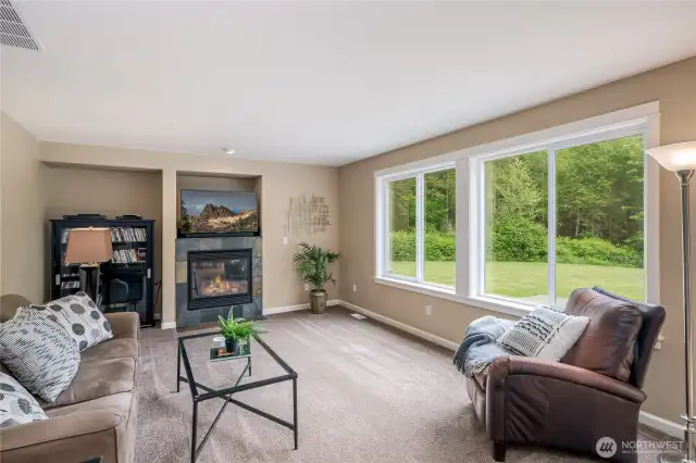 Family room offers propane fireplace and huge windows that bring in the outdoors.