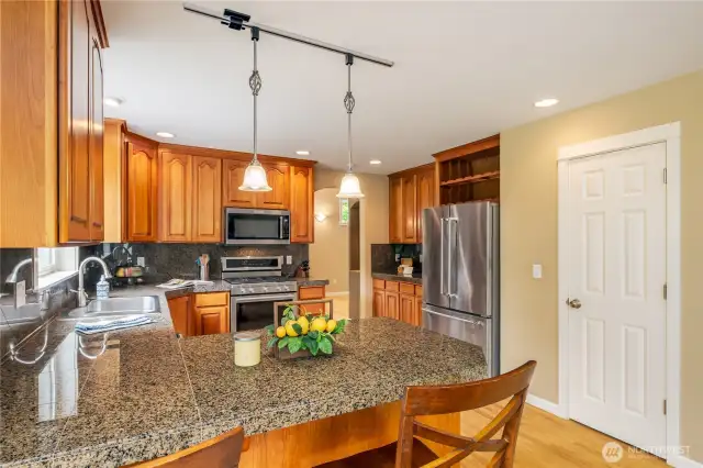 This view of kitchen showcases door to walk-in pantry as well as additional cabinetry, perhaps used as a butlers pantry as you head to dining room. Note the built-in wine rack above, set in refrigerator.