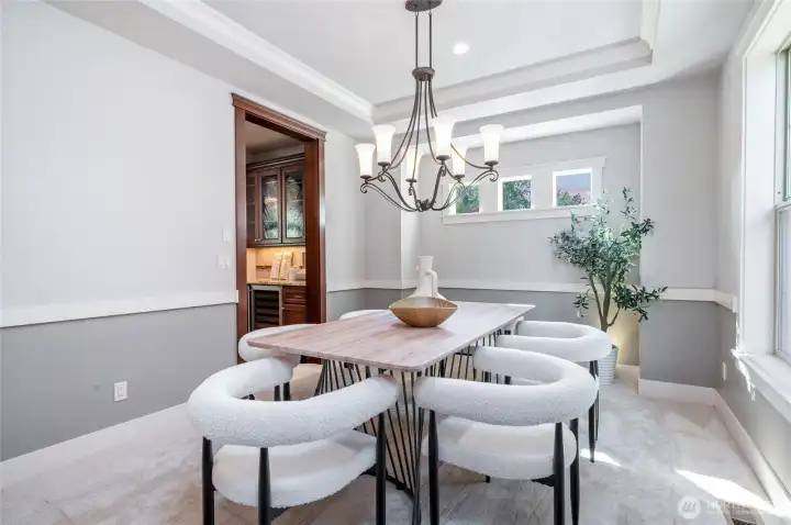 Formal dining room with recessed ceiling and adjacent Butler's bar and walk-in pantry.