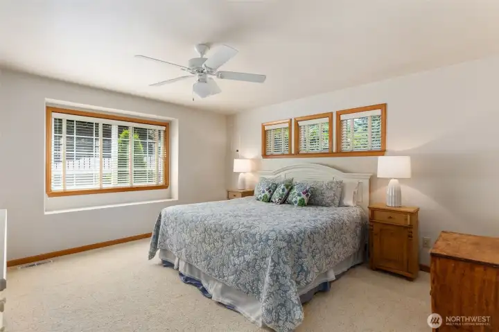 Main floor primary bedroom has lots of light, ceiling fan and walk in closet