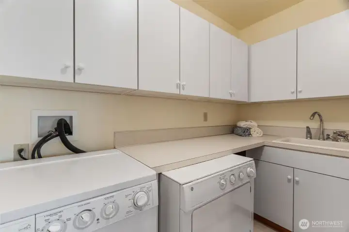 Lower level laundry room with utility sink and lots of cabinet and counter space for folding