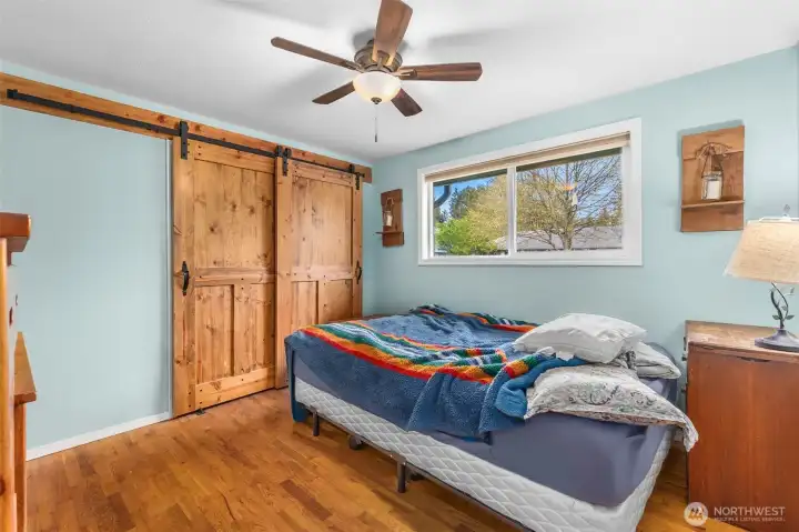 Secondary bedroom with rich hardwood flooring.